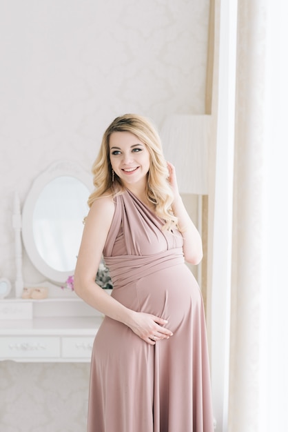 Blonde femme enceinte posant à l'intérieur