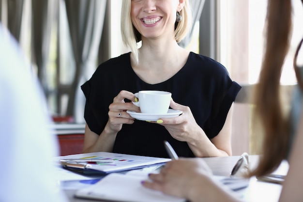 Blonde femme parlant à des amis dans un café pour une tasse de café