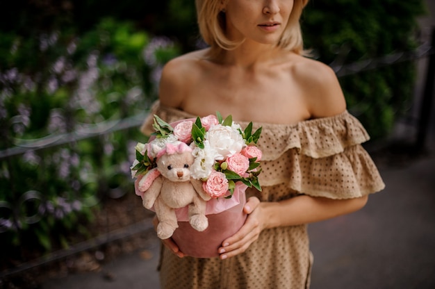 Blonde femme tenant une boîte remplie de fleurs