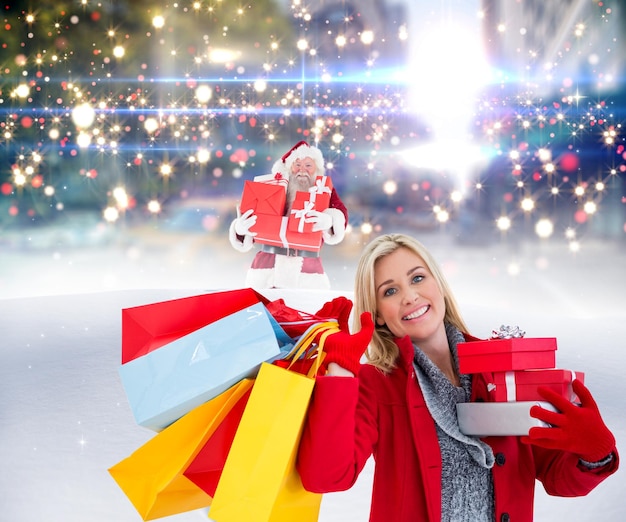 Blonde festive tenant de nombreux cadeaux contre le père Noël livrant des cadeaux en ville