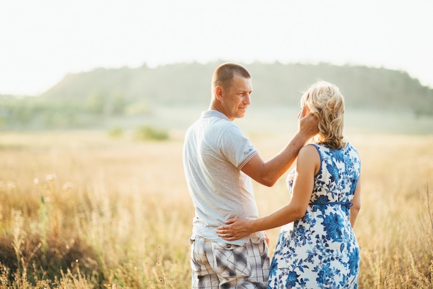 Blonde fille enceinte maman vêtue d'une robe bleue et un homme dans un champ