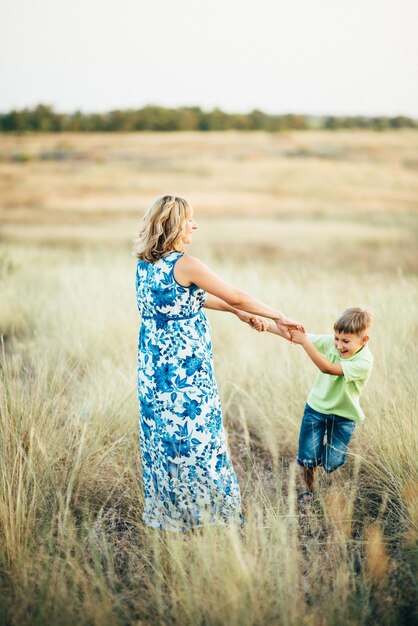 Blonde fille enceinte maman vêtue d'une robe bleue s'amuse avec son fils