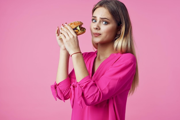 Blonde gaie dans une collation de restauration rapide pour hamburger chemise rose