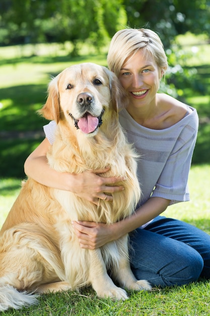Blonde heureuse étreignant son chien dans le parc