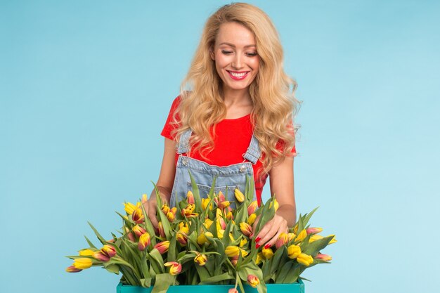 Blonde jeune femme avec bouquet de tulipes sur bleu