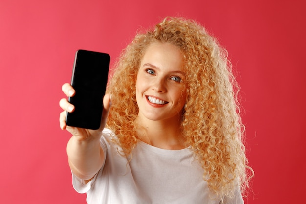 Blonde jeune femme montrant l'écran du smartphone noir
