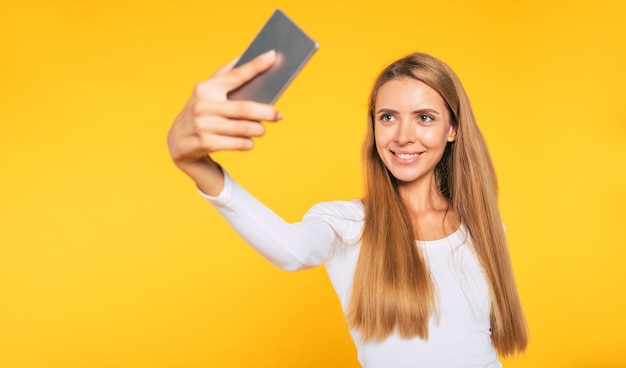Blonde jeune femme séduisante avec smartphone. Photo selfie sur téléphone portable. Image heureuse