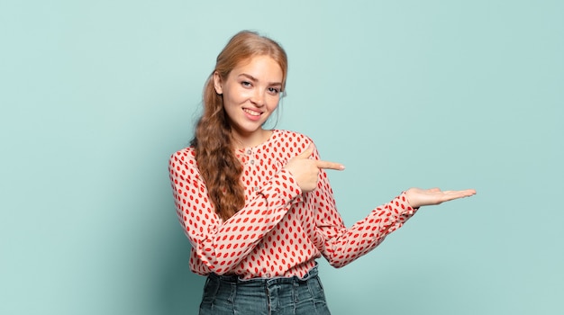 Blonde jolie femme souriante, se sentir heureuse, insouciante et satisfaite, pointant vers un concept ou une idée sur l'espace de copie sur le côté