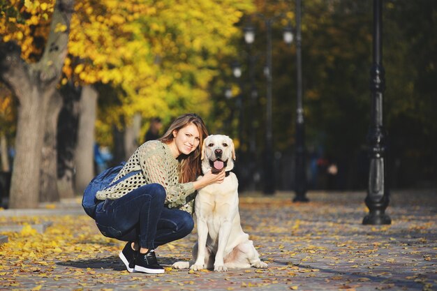 Blonde jouant avec son labrador dans le parc de l'automne