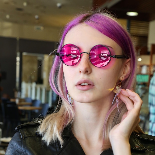 blonde avec des mèches de cheveux lilas dans des verres rose vif