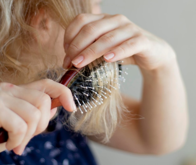 Blonde peignant les cheveux mouillés et emmêlés Jeune femme peignant ses cheveux emmêlés après la douche