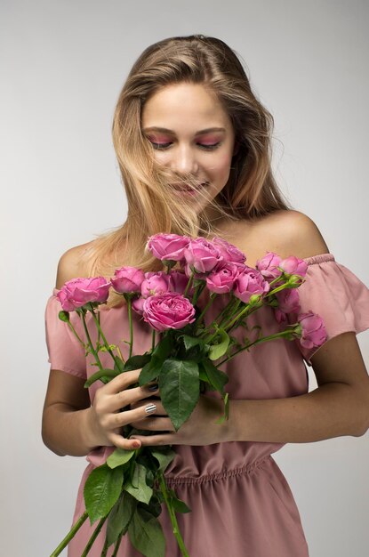 Photo blonde souriante adolescente avec un bouquet de fleurs isolé sur fond gris saint valentin