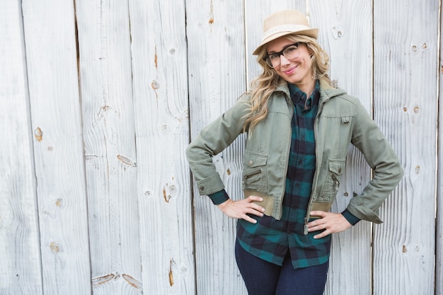 Blonde souriante au chapeau posant avec les mains sur les hanches