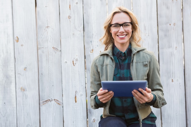 Blonde souriante dans des verres à l&#39;aide de tablet pc