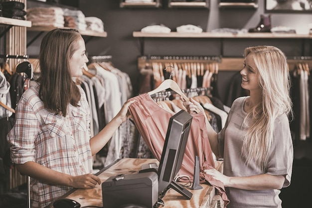 Blonde souriante faisant du shopping dans un magasin de vêtements