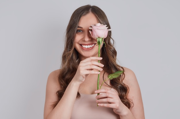 Blonde souriante avec de longues boucles, couvrit ses yeux d'une rose.