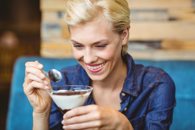 Blonde souriante mangeant un chocolat crémeux