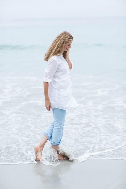 Blonde souriante marchant au bord de la mer