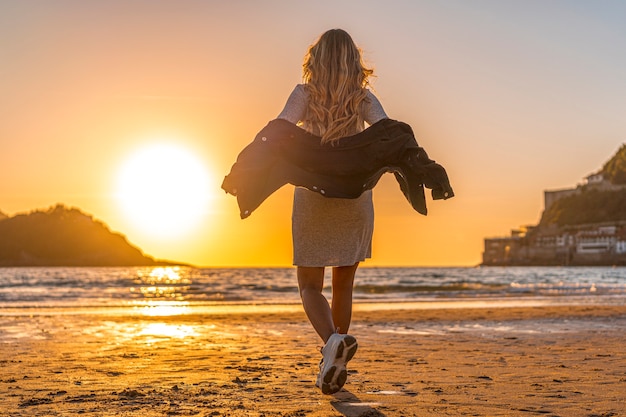 Une blonde souriante avec pull gris dans une session de style de vie sur une plage