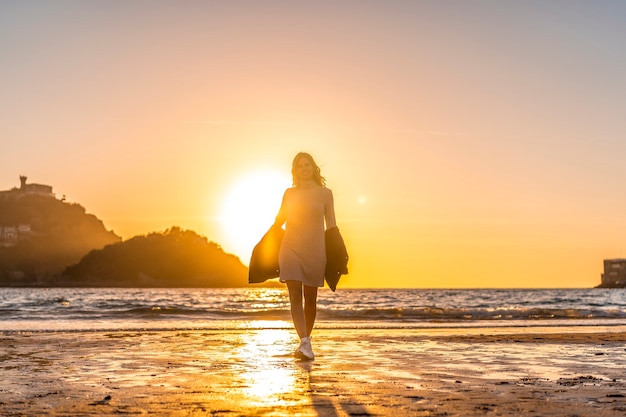 Une blonde souriante avec pull gris dans une session de style de vie sur une plage