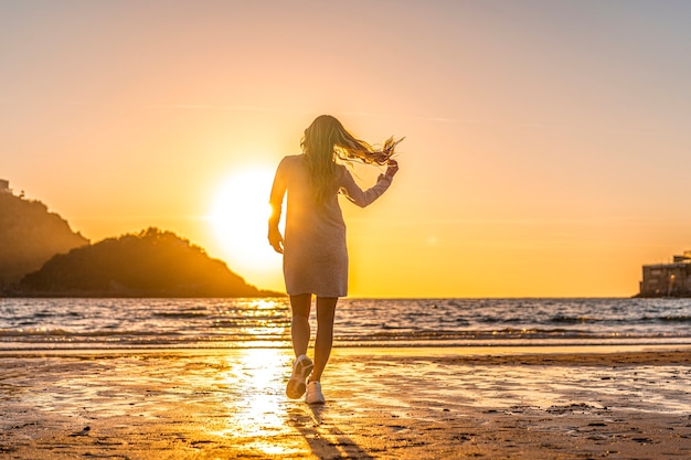 Une blonde souriante avec pull gris dans une session de style de vie sur une plage