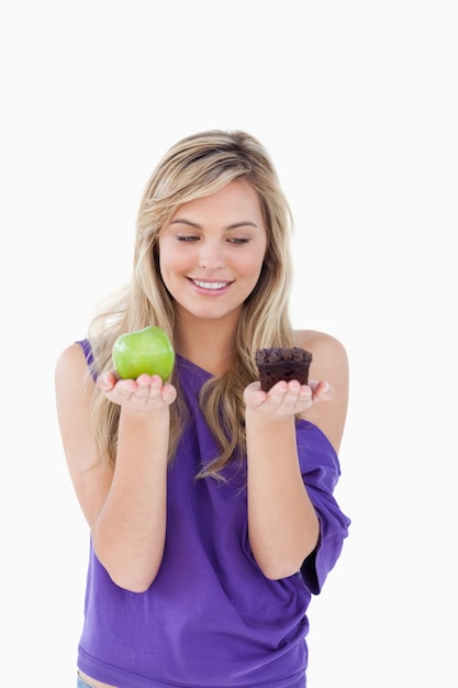 Blonde souriante tenant une pomme et un muffin