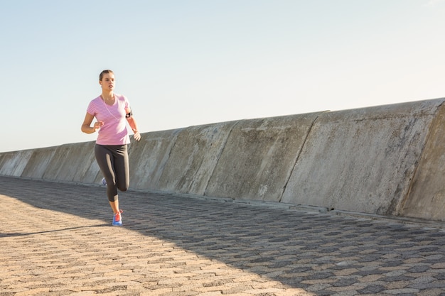 Blonde sportive, faire du jogging sur la promenade