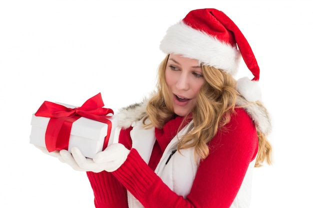 Blonde surprise au chapeau de père Noël tenant un cadeau