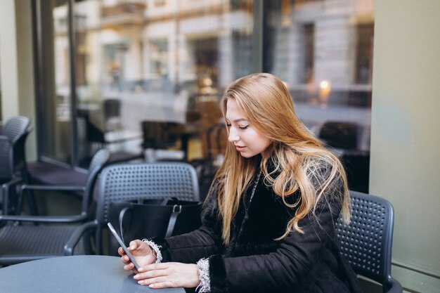 Blondie caucasian girl sitting in cafe avec smartphone