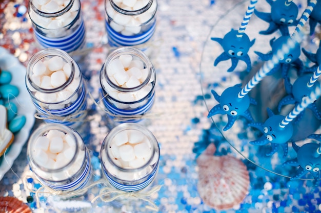 Blue cake apparaît des poulpes amusantes partagées sur la plaque ronde en verre et les pots avec de la guimauve.