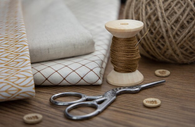 Une bobine de ciseaux à boutons de fil et de tissus de coton sur la table