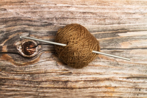 Photo bobine de laine brune et une aiguille au crochet sur un fond en bois