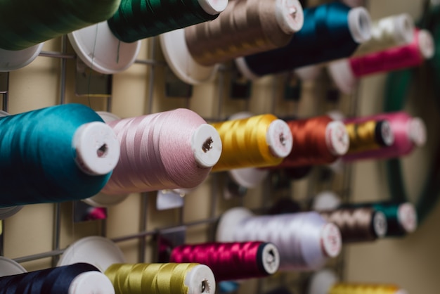 Des bobines de fil suspendues dans un atelier de couture. Des écheveaux pour machine à coudre sont suspendus dans un atelier de couture.