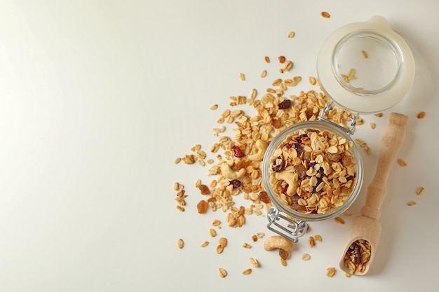 Bocal en verre et cuillère avec granola isolé