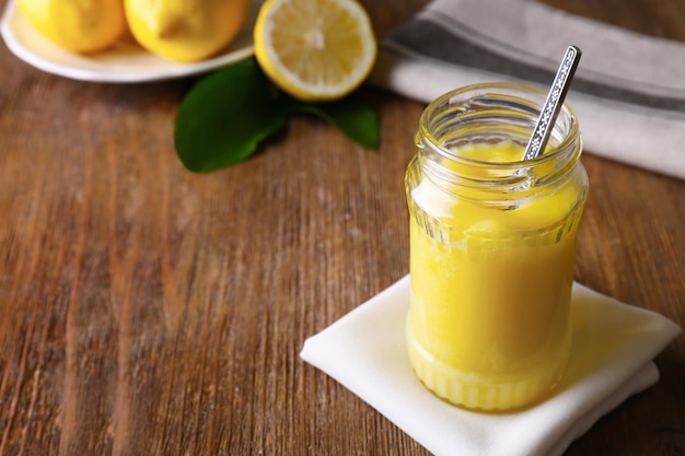 Bocal en verre avec une délicieuse crème au citron sur une table en bois