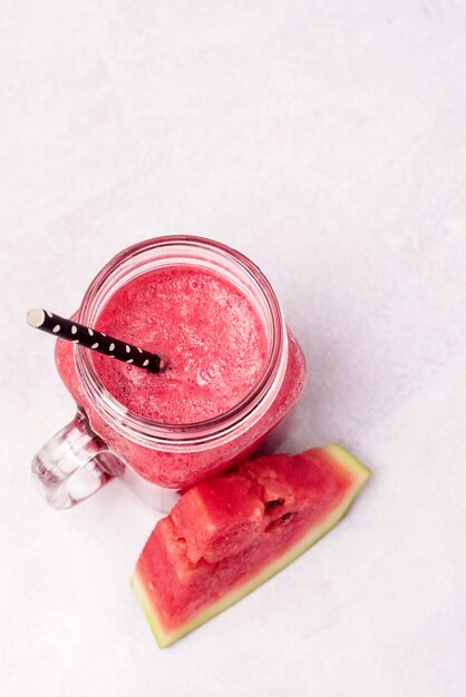 Bocal en verre de délicieux smoothie pastèque sur fond bleu vertical boisson d'été saine et savoureuse