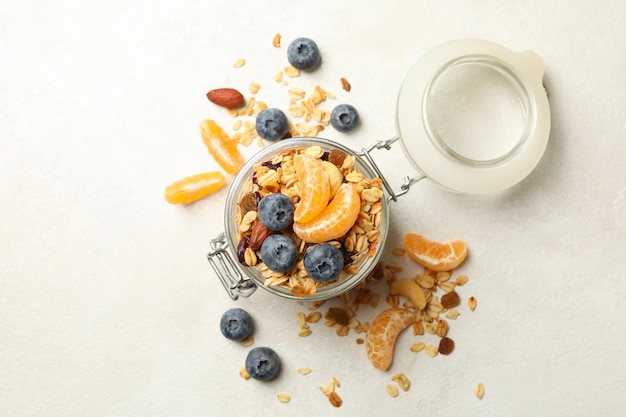 Bocal en verre avec du granola savoureux sur fond blanc