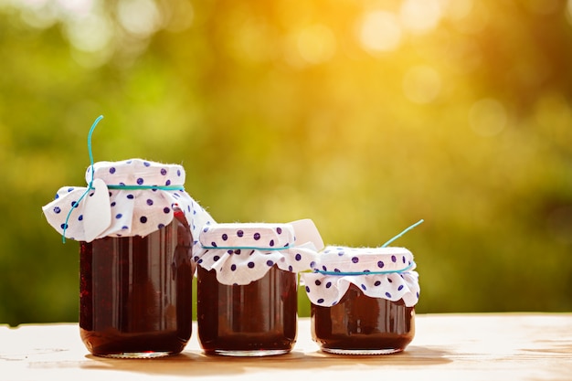 Bocaux de confiture de baies sur fond de nature verdoyante.