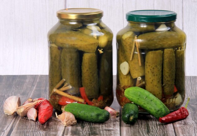 Bocaux en verre avec cornichons sur une table en bois. Concombres en conserve