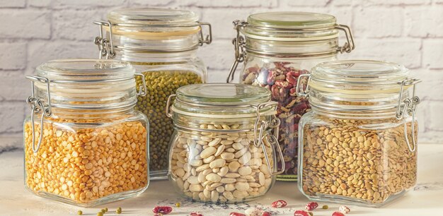 Bocaux en verre avec diverses légumineuses, haricots mungo, pois et lentilles