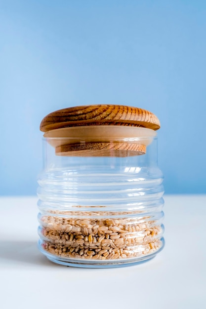 Bocaux en verre sur fond bleu avec espace de copie pour le texte Concept zéro déchet cuisine de style maison Concept écologique et de réutilisation Gruau d'aliments bio bio dans des bocaux en verre sur une table blanche dans la cuisine