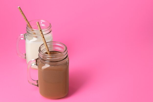 Bocaux en verre avec milkshakes aromatisés sur fond rose