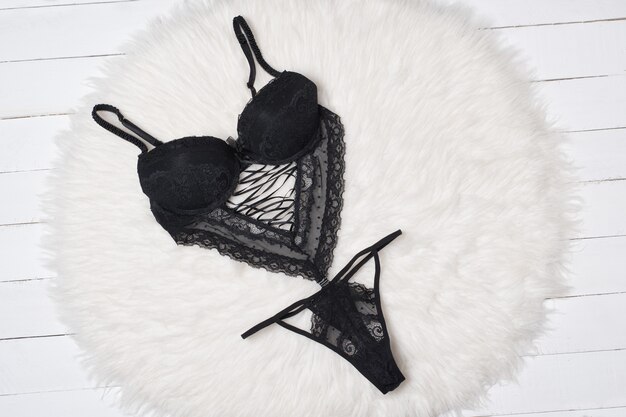 Body en dentelle noire sur fourrure blanche. Concept de lingerie de mode. Fermer