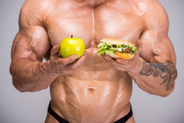 Bodybuilder adulte tient la pomme dans sa main.