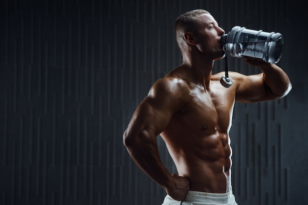 Bodybuilder boire de l'eau après l'entraînement de fitness