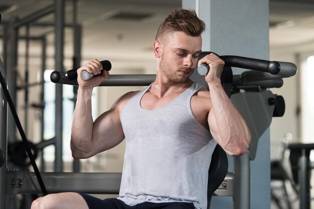 Bodybuilder exerçant des épaules sur la machine