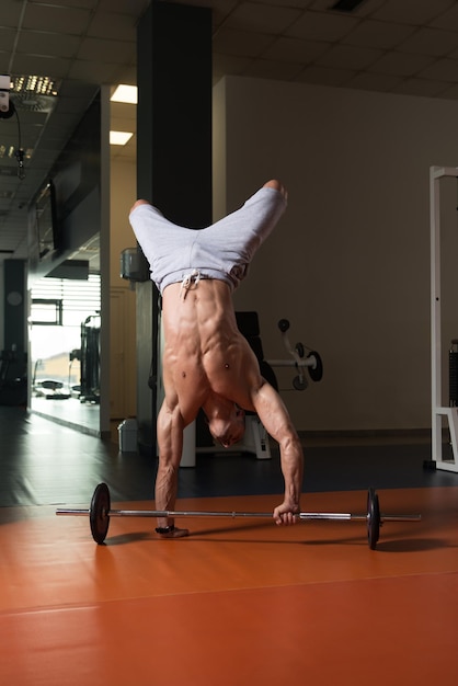 Bodybuilder exerçant des pompes sur le poirier dans la salle de gym