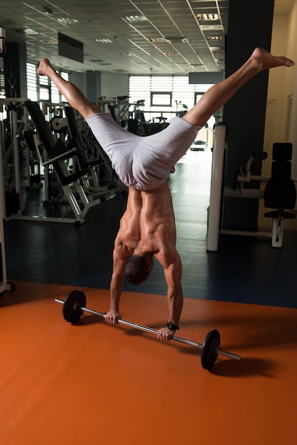 Bodybuilder exerçant des pompes sur le poirier dans la salle de gym