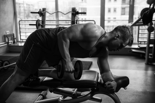 Bodybuilder exerçant des triceps avec des haltères dans la salle de gym