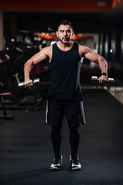 Bodybuilder faisant de l'exercice pour les muscles de l'épaule, deltoïde avec haltère dans le gymnase